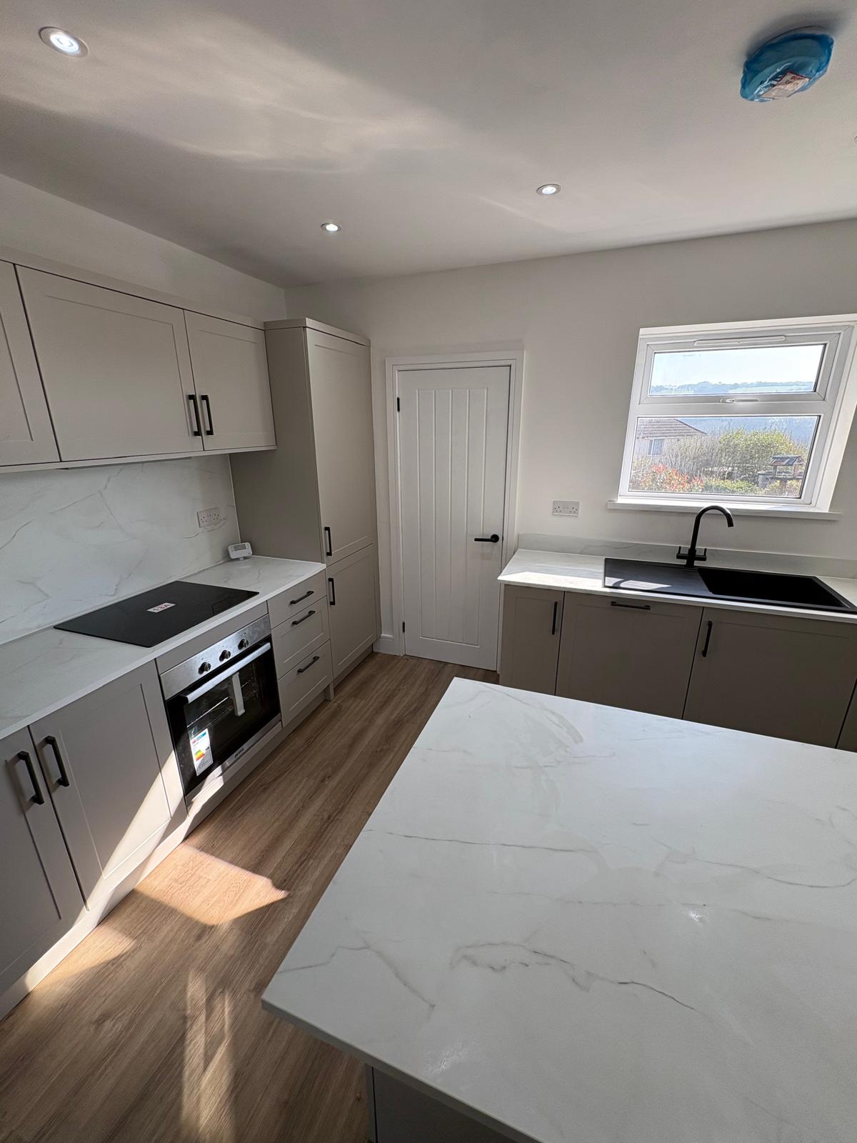 Finished kitchen with marble worktops and window view